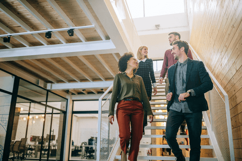 four employees talking as they walk down the stairs